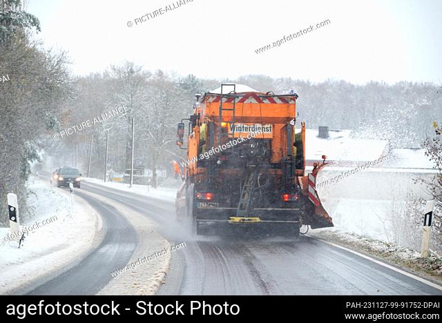 27 November 2023, Rhineland-Palatinate, Idenheim: A winter road clearance vehicle clears snow from the L2 and spreads salt