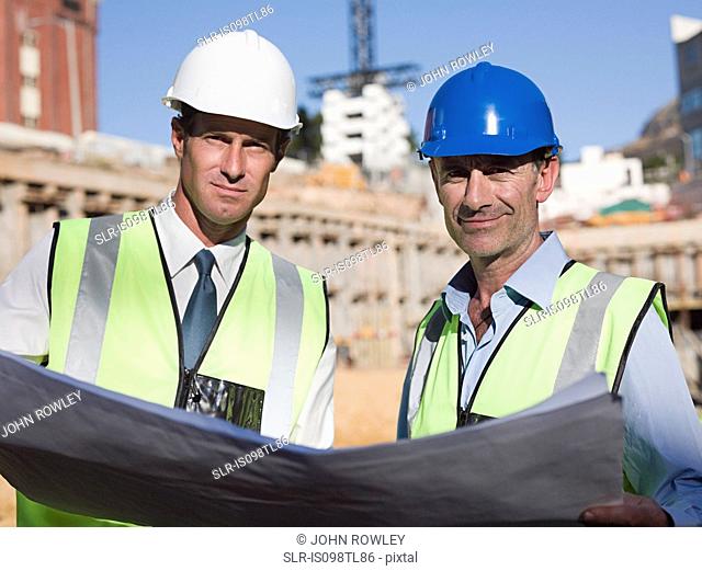 Mature men with blueprint on construction site