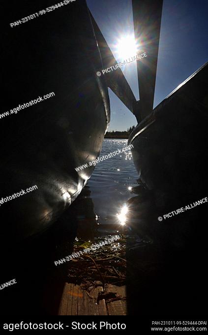 11 October 2023, Bavaria, Aitrang: Water glistening in the sunshine reflects off a rowboat on the shore of Lake Elbe. Photo: Karl-Josef Hildenbrand/dpa