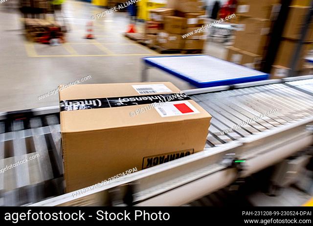 07 December 2023, Lower Saxony, Großenkneten: A box of technical items is transported on a conveyor belt to storage in the incoming goods area of Amazon's new...