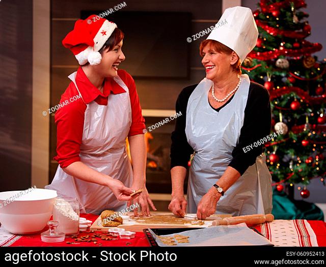 Happy mum and daughter laughing at baking christmas cake