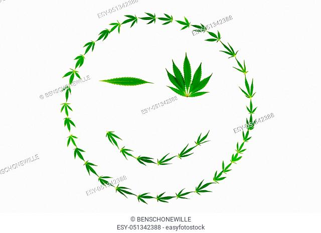 Winking smiling face made of cannabis leaves isolated on white background
