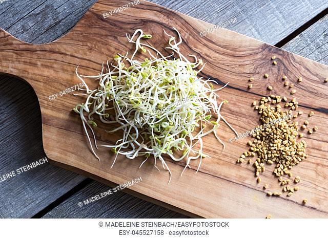 Sprouted and dry fenugreek seeds on a wooden cutting board