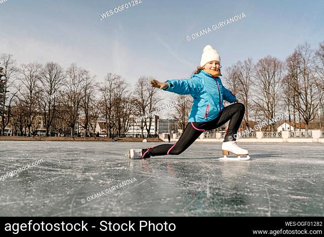 Girl with arms outstretched skating on ice