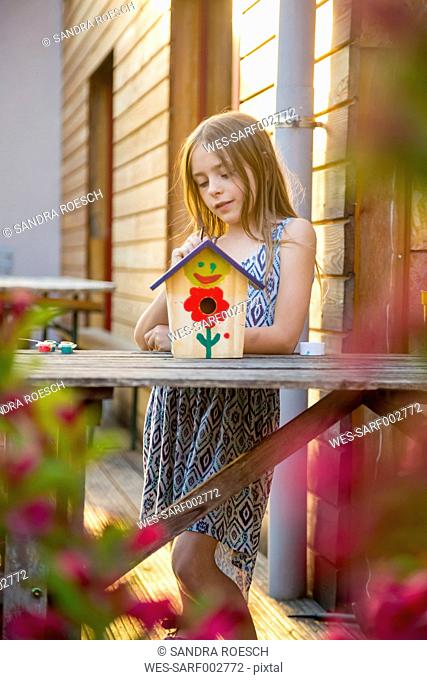 Portrait of girl with painted birdhouse