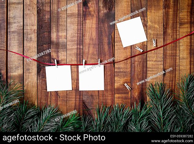 Blank photo paper attach to rope with clothespins on wood table background. Flat lay