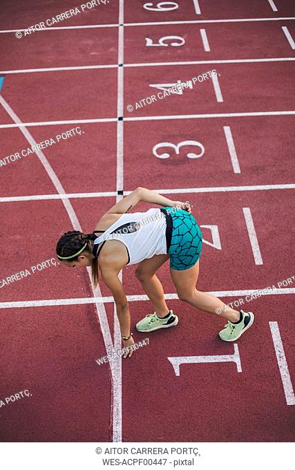 Top view of female runner in starting position on tartan track