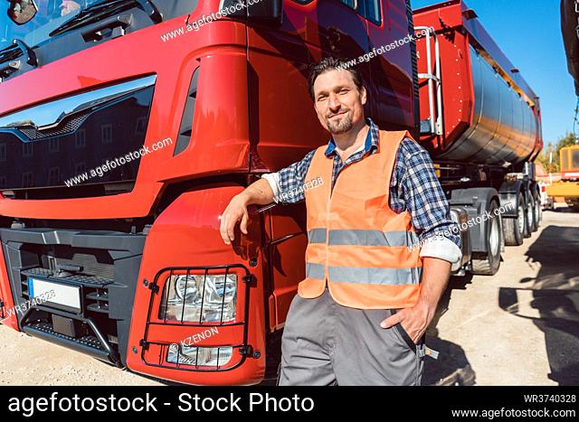 Truck driver in front of his freight forward lorry looking at camera