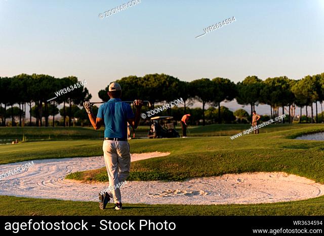 golfer from back looking to ball and hole in distance, handsome middle eastern golf player portrait from back with beautiful sunset in background