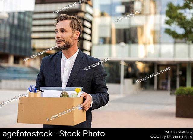 Businessman carrying cardboard box outside office building