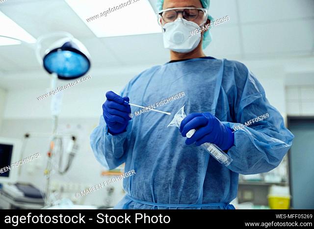 Emergeny doctor putting a swab into a tube in hospital