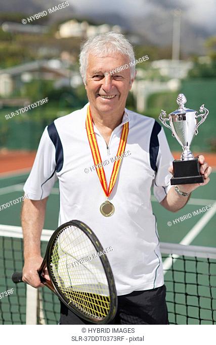 Older man with trophy on tennis court