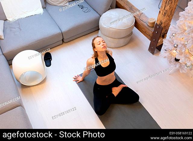 Beautiful blonde woman doing home workout indoors. Woman practice yoga at home. Fit girl using workout tutorials for healthy active lifestyle