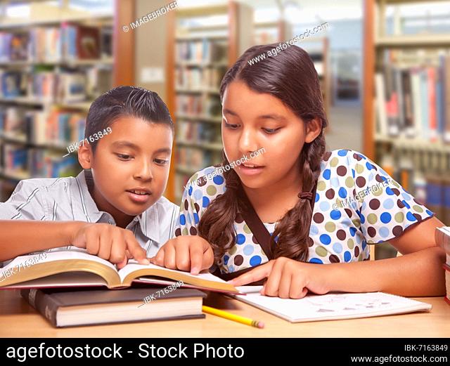 Hispanic boy and girl having fun studying together in the library