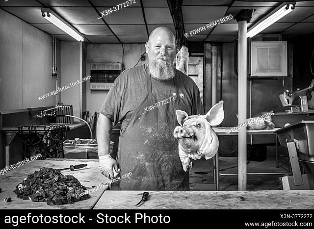 Butcher holding onto pig head at Sudlersville Meat Locker in Maryland