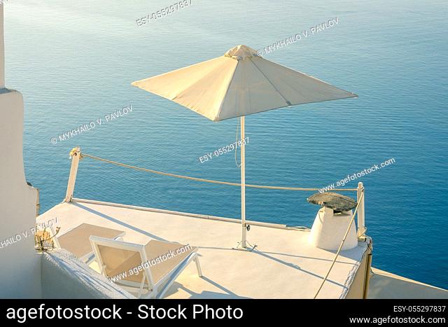Greece. A quiet summer evening in Santorini. Two sun loungers and an umbrella on the balcony with a sea view