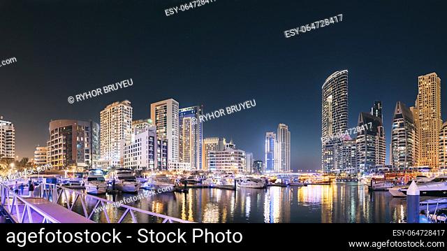 Dubai Marina Port, UAE, United Arab Emirates - Beautiful Night View Of Dubai Marina Towers. Yachts Moored Near City Pier, Jetty In Evening Night Illuminations