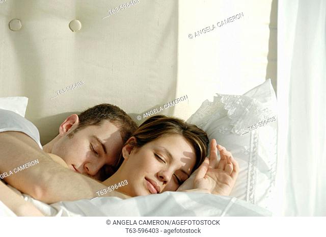 Young couple sleeping and cuddling in bed together