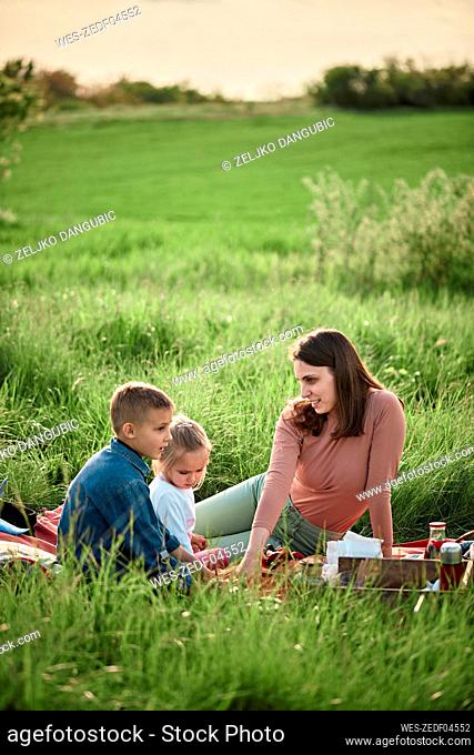 Mother talking to children in field on weekend