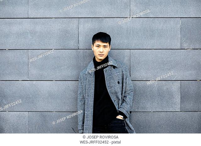 Portrait of stylish young man wearing black turtleneck pullover and grey coat
