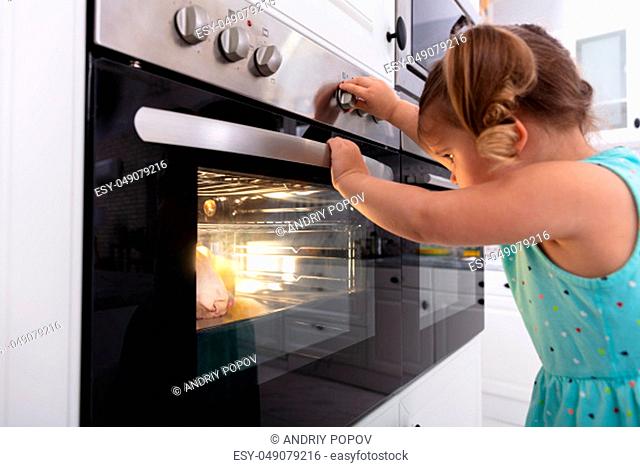 Little Girl Playing With Electric Microwave Oven In The Kitchen