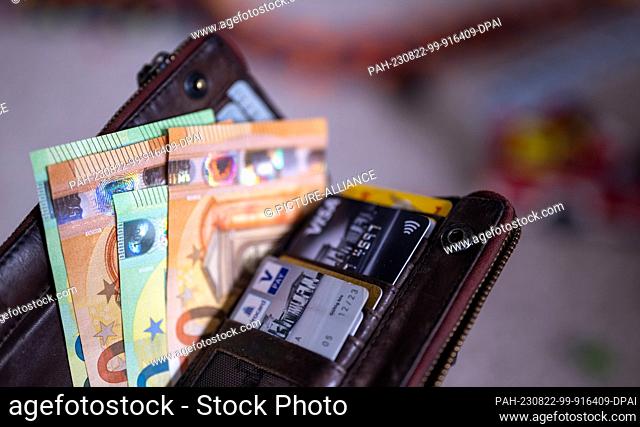 ILLUSTRATION - 21 August 2023, Berlin: Banknotes with the value of 100 and 50 euros are in a wallet together with credit cards and giro cards