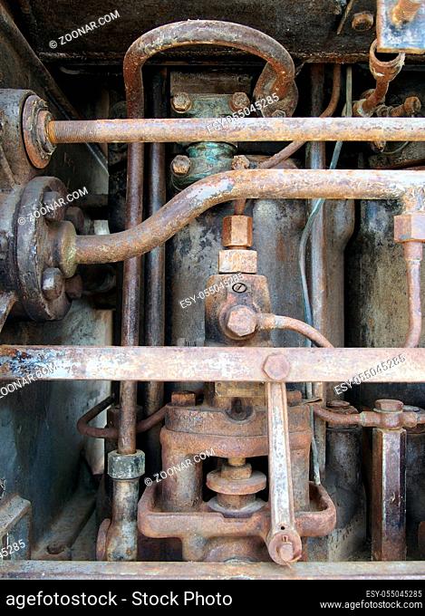 close up of a large old abandoned marine diesel engine showing rusting pipes and cylinders and bolts
