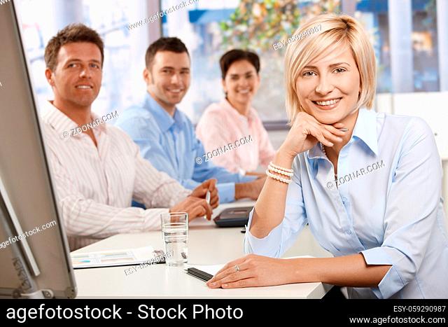 Happy businesswoman on business meeting at office, leaning on table, looking at camera and smiling