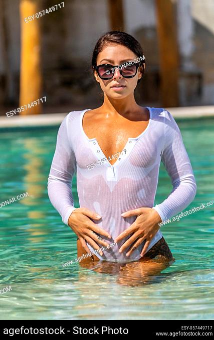 A gorgeous brunette model enjoys a day at the pool on a Caribbean island