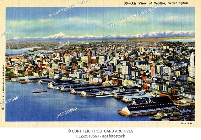 Aerial view of Seattle, Washington, USA, 1935. Vintage linen postcard. A harbour with docks is in the foreground and the snow-capped mountains rise up in the...