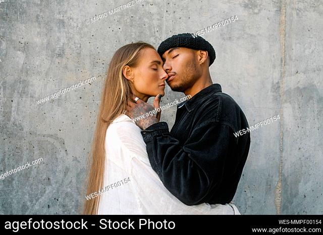 Man embracing woman standing in front of wall