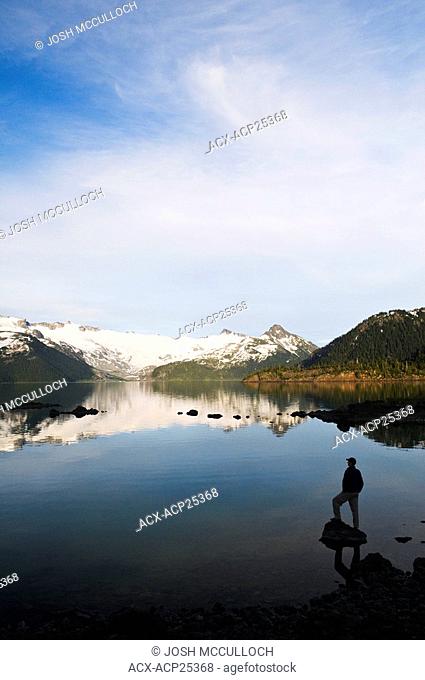 A hiker is silhouetted by the Sphinx Glacier and Garibaldi Lake in Garibaldi Provincial Park near Whistler BC