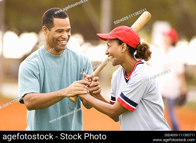 Man teaching girlfriend to play baseball