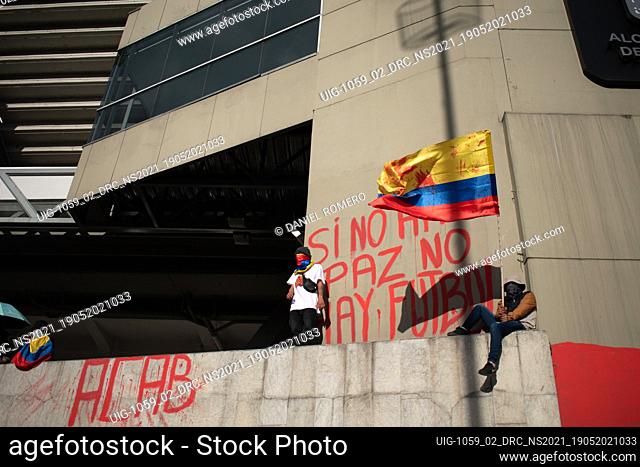 Protester waves the Colombian flag while next to him there is a mural that says ""if there is no peace, there is no football"" against the realization of the...