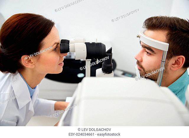 health care, medicine, people, eyesight and technology concept - optometrist with non contact tonometer checking patient intraocular pressure at eye clinic or...