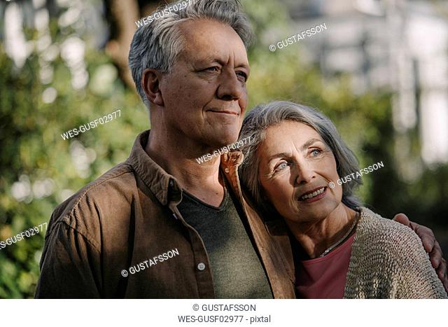 Portrait of confident senior couple in garden of their home in autumn