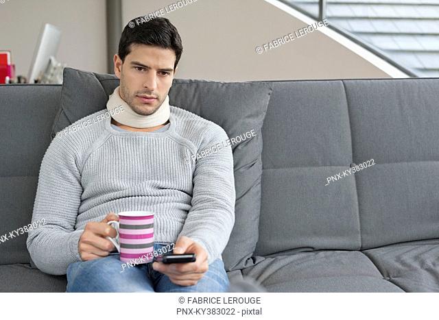 Man suffering from neckache and watching television