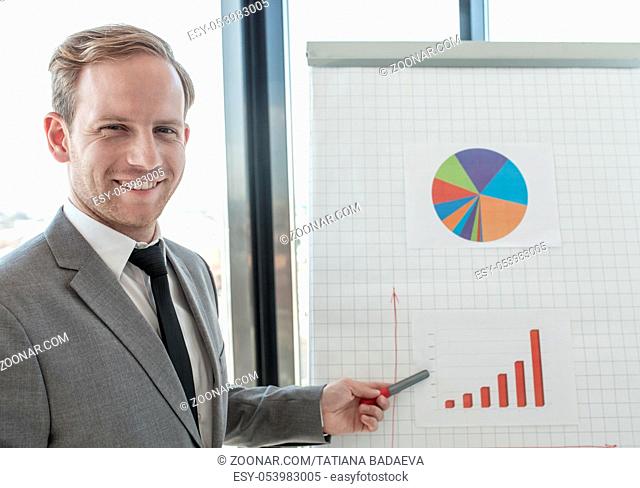 Business man making presentation of reports in diagrams and graphs at flip chart in offfice