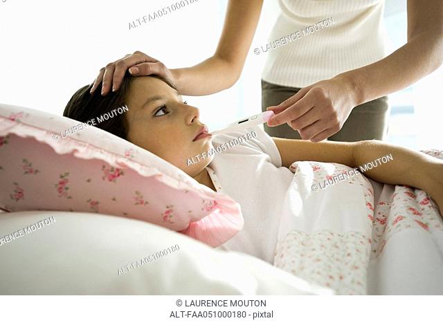 Mother checking daughter's temperature, caressing forehead