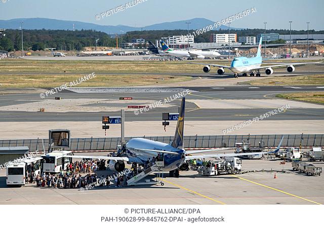 28 June 2019, Hessen, Frankfurt/Main: Numerous passengers board a Ryanair passenger plane on the apron of Frankfurt Airport