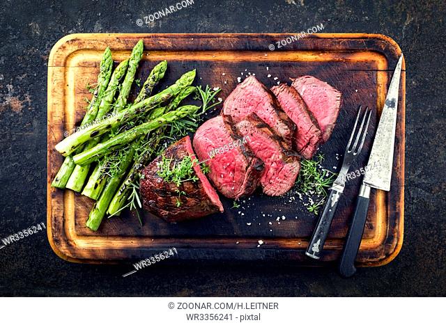 Barbecue Wagyu Point Steak with green Asparagus as close-up on burnt cutting board