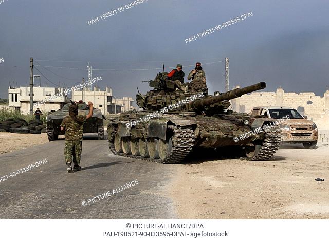 21 May 2019, Syria, Kafr Nabudah: Syrian opposition fighters ride a tank as they head to the front lines in the countryside of Hama Province