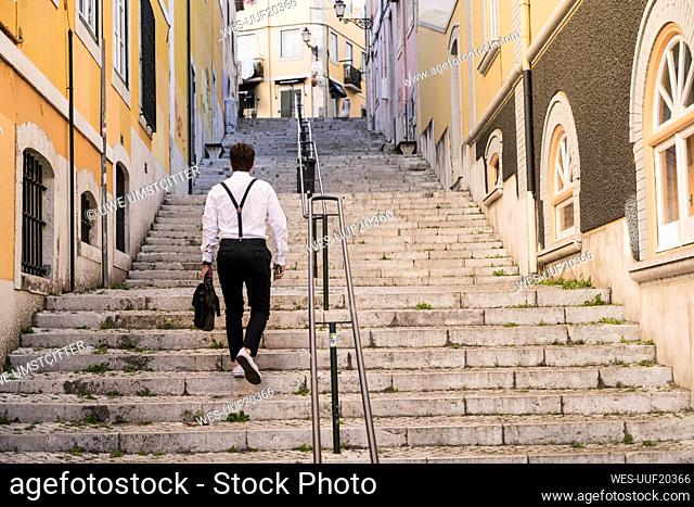 Rear view of young man walking up stairs in the old town, Lisbon, Portugal