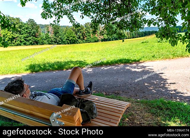 Europe, Germany, Baden-Wuerttemberg, Rems-Murr-Kreis, Murrhardt, hiker takes a break on a panoramic wooden lounger