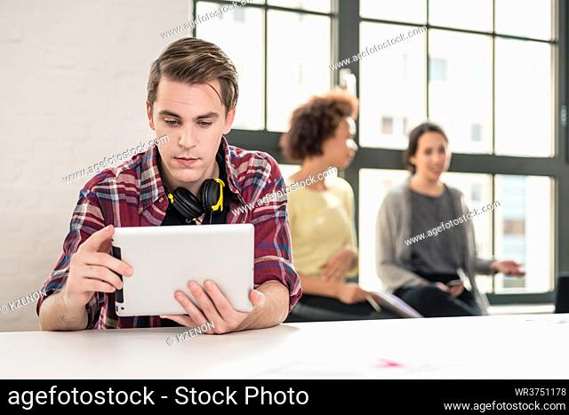 Young man using headphones while watching a video on tablet PC at work in the meeting room