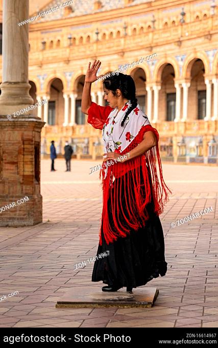 Seville, Spain - 10 January, 2021: passionate flamenco dancer woman in colorful clothes dancing at the Plaza de Espana in Seville