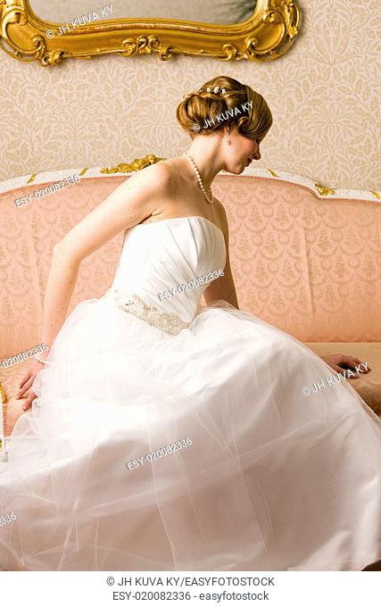 Beautiful bride sits on the pink couch