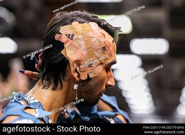 16 January 2023, Berlin: With numerous plasters on his head, an activist walks the catwalk at a performance disguised as an Adidas show during Berlin Fashion...