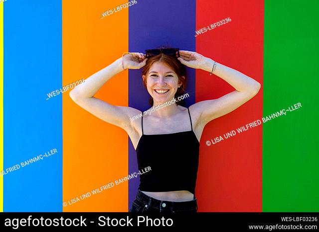 Italy, Province of Cuneo, ¶ÿBarolo, Portrait of young beautiful woman posing in front of colorful wall of Chapel of Barolo