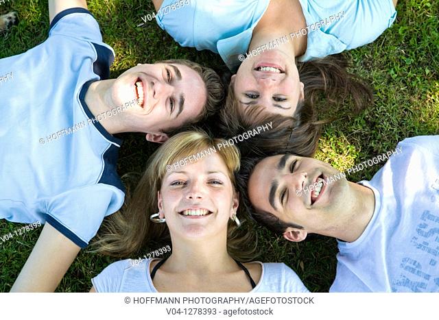 Four young people smiling up at the camera, Germany, Europe
